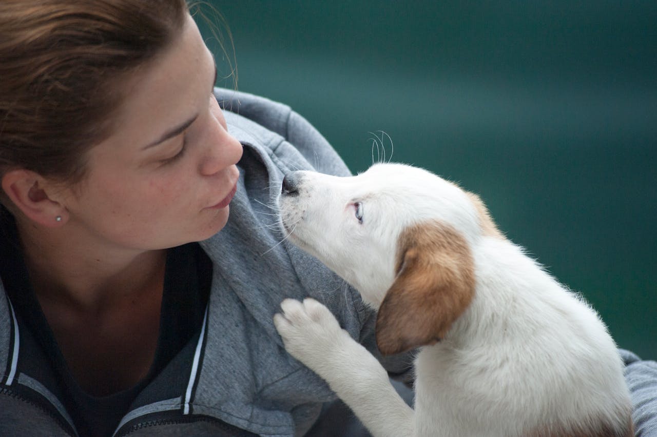 gallery-2 A candid shot of a woman and puppy sharing a tender moment outdoors.